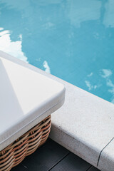 Corner of deck chair near swimming pool under sunlight. Exterior design. Resting in vacation on summer season. 