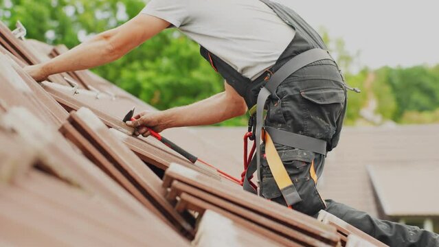 Closeup of roofer putting back roof tiles after adding solar panel mounts