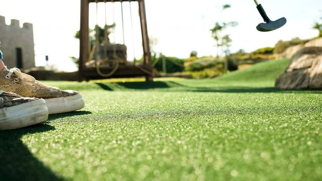 Woman makes a putt on artificial grass of mini-putt course