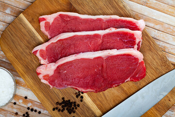 Pieces of beef with peas of bitter pepper on cutting board