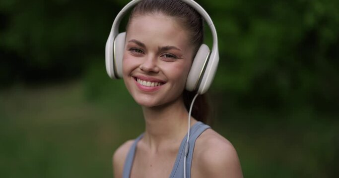 The girl with the big white headphones turns her head and looks at the camera with a smile