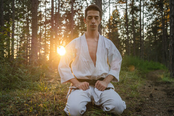 One man caucasian karateka meditate during karate training practice in the woods mind peace and strength concept copy space wear white kimono gi uniform © Miljan Živković