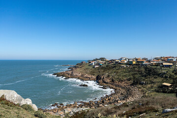 Small bucolic bay with blue sky and waves crashing on the rocks