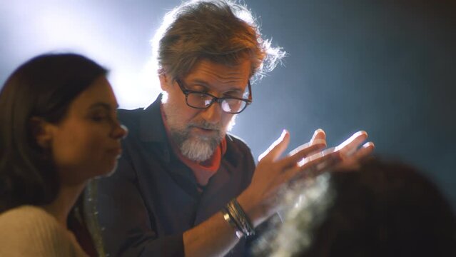 During the rehearsal of the performance on the stage with a spotlight, director giving instructions on the script to the actors of the theater and talking