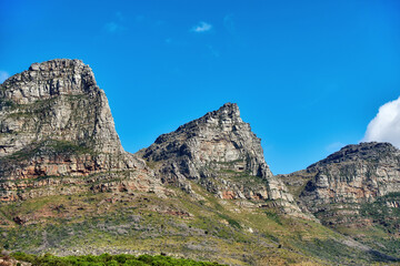 Beautiful outdoor mountain landscape with a blue sky copyspace in nature. Outside view of high mountains, green grass, and plant life. Relaxing natural background of rock formations on a summer day