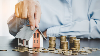 House model with stack coins, business hand is planning savings money of coins for buy home....