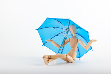 Wooden man under a blue umbrella. Insurance concept.