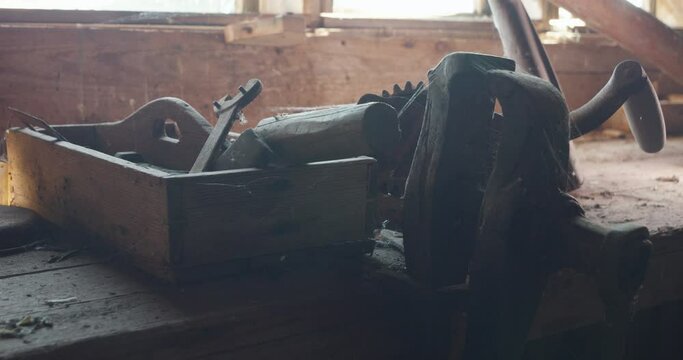 Old dusty workdesk and rusty tools in toolbox backlit by window, dolly shot