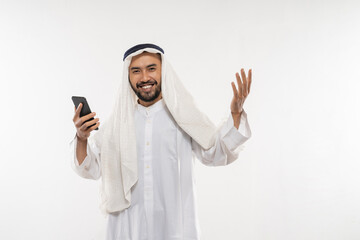 excited young man in a turban using a mobile phone happily looking at the screen with an excited expression on a plain background