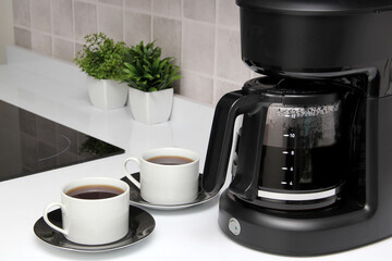 Freshly prepared coffee in a filter coffee machine served in white cups that is rich in antioxidants, fights Alzheimer's and Parkinson's, produces tachycardia and insomnia
