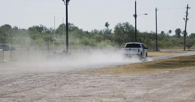 A US Border Patrol truck drives along a dusty two track near a baseball field along the US-Mexico border near La Joya, Texas.