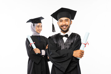 Male graduate student wearing a togas holding a certificate standing in front of his friend on an isolated background