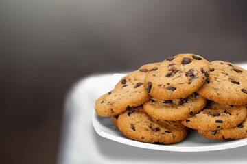 Tasty homemade cookies with chocolate chips in plate on the desk