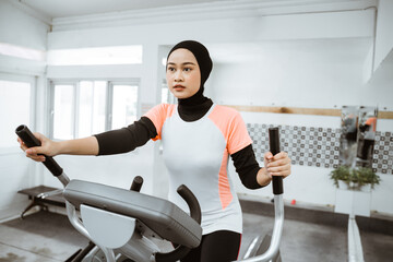 muslim women at the gym doing cardio exercises on static elliptical cycle machine