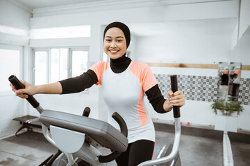 smiling beautiful women at the gym doing exercises on static elliptical cycle machine