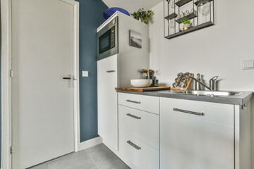 Interior of modern bathroom with bathtub and sink in wooden counter furnished with wooden shelf rack