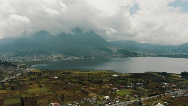 Imbabura Volcano In Clouds With San Pablo Lake In Foreground In Rural Town Of Otavalo In Ecuador. wide aerial drone