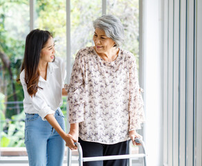 Asian young beautiful happy female granddaughter smiling helping cheerful old senior healthy gray...