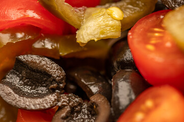 Vegetable salad of tomatoes, black olives and pickled Jalapeno pepper, seasoned with olive oil.