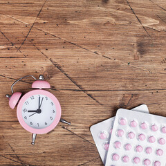 women health concept. copy space. pills and clock on brown wooden background. wellness, medicine,...