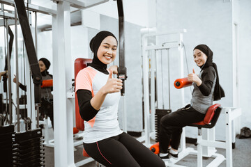 Fototapeta premium muslim asian woman working out at the gym and showing thumb up