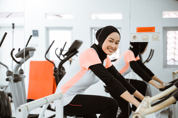attractive muslim woman exercising with static bike at the gym