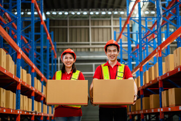 Warehouse workers, Asian men and women in vests and helmets, work to inspect goods or packages on...