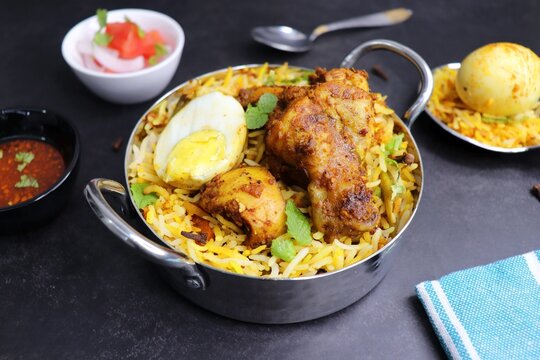 Chicken Biryani or murgh Pulao. Garnished with fried onion, mint leaves, and Boiled egg. Biryani is a famous Spicy nonvegetarian dish of India. Chicken cooked along with Basmati rice. Cucumber Raita.