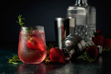 Cocktail with ice, strawberries, and rosemary.