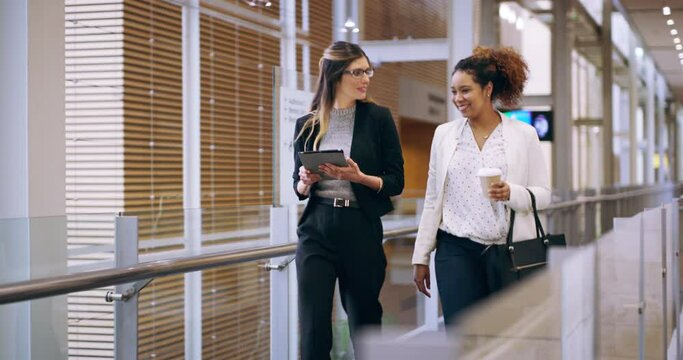 Happy business women talking, making conversation and walking through their office building together in the morning. Cheerful, diverse and smiling female colleagues discussing work and a strategy