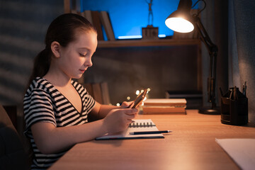 Positive teen girl using doing homework sitting at desk using tablet pad computer, enjoying distance homeschooling at night. Children and education