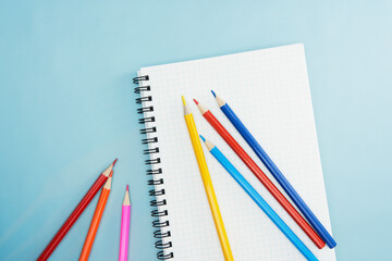 明るい水色の中のノートの上の綺麗な色鉛筆