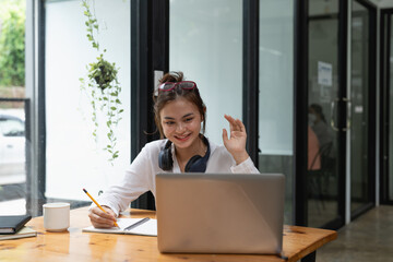 Online education, e-learning. young woman studying remotely, using a laptop, listening and taking note. online webinar at home