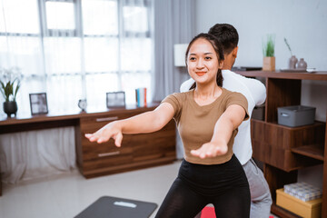 Fototapeta na wymiar portrait of young asian couple workout together at home stretching their body