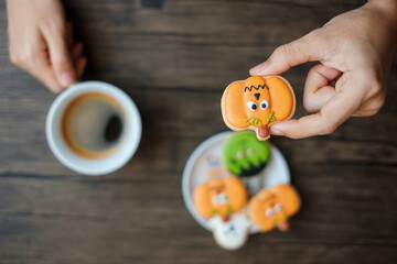 hand holding coffee cup during eating funny Halloween Cookies. Happy Halloween day, Trick or...