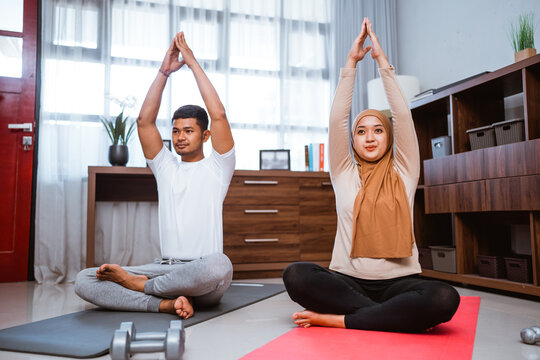 Asian Couple Doing Partner Workout And Stretching Together At Living Room