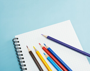 水色の机の上のノートにあるカラフルな色鉛筆