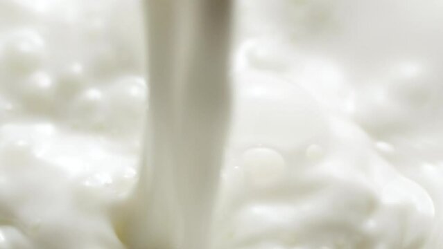 Macro slow motion pouring white milk, closeup splashing fresh drink with bubbles