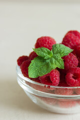 Close up fresh raspberries in the clear glass bowl on the white background