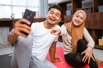 muslim couple using mobile phone together after exercising at home
