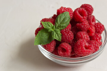 Fresh raspberries (close up) in the clear glass bowl on the white background