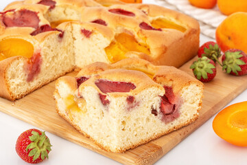 Fresh homemade sponge summer fruit pie with apricot and strawberries. Handmade sweet pastry with fruits.