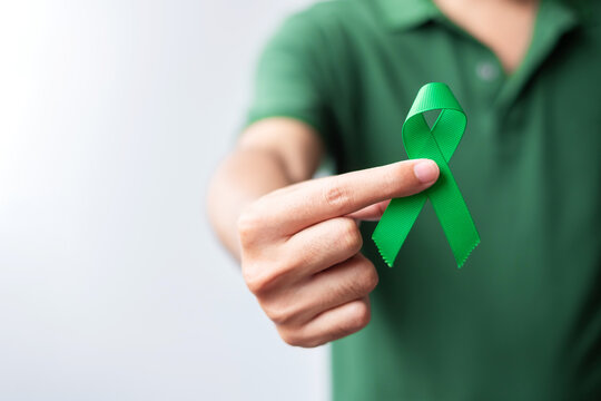 Hand holding green Ribbon for Liver, Gallbladders, bile duct, cervical, kidney Cancer and Lymphoma Awareness month. Healthcare and world cancer day concept
