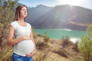 Pregnant woman walking in park during summer. Pregnancy care