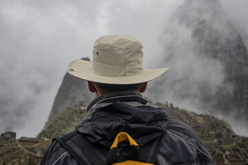 Man with hat looking at Machu Picchu