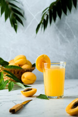 fresh apricot juice contains many vitamins, apricot and juice, green twigs in the background, cold drink, sweet summer cocktail 