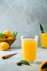 fresh apricot juice contains many vitamins, apricot and juice, green twigs in the background, cold...