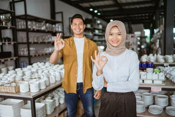 Fototapeta na wymiar Beautiful asian muslim woman smiling while standing with okay hand gesture in houseware store