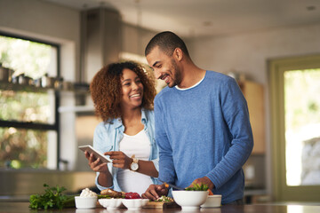 Our food looks just as good as the recipe. Shot of a happy young couple using a digital tablet...