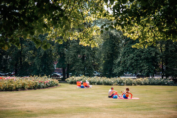 People are sunbathing on the grass in the park in the UK
